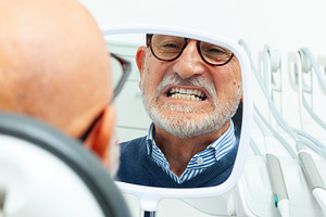 Senior man checking his teeth in the mirror at the dentist's office, a Health & Medical Photo by Antonio Gravante Market
