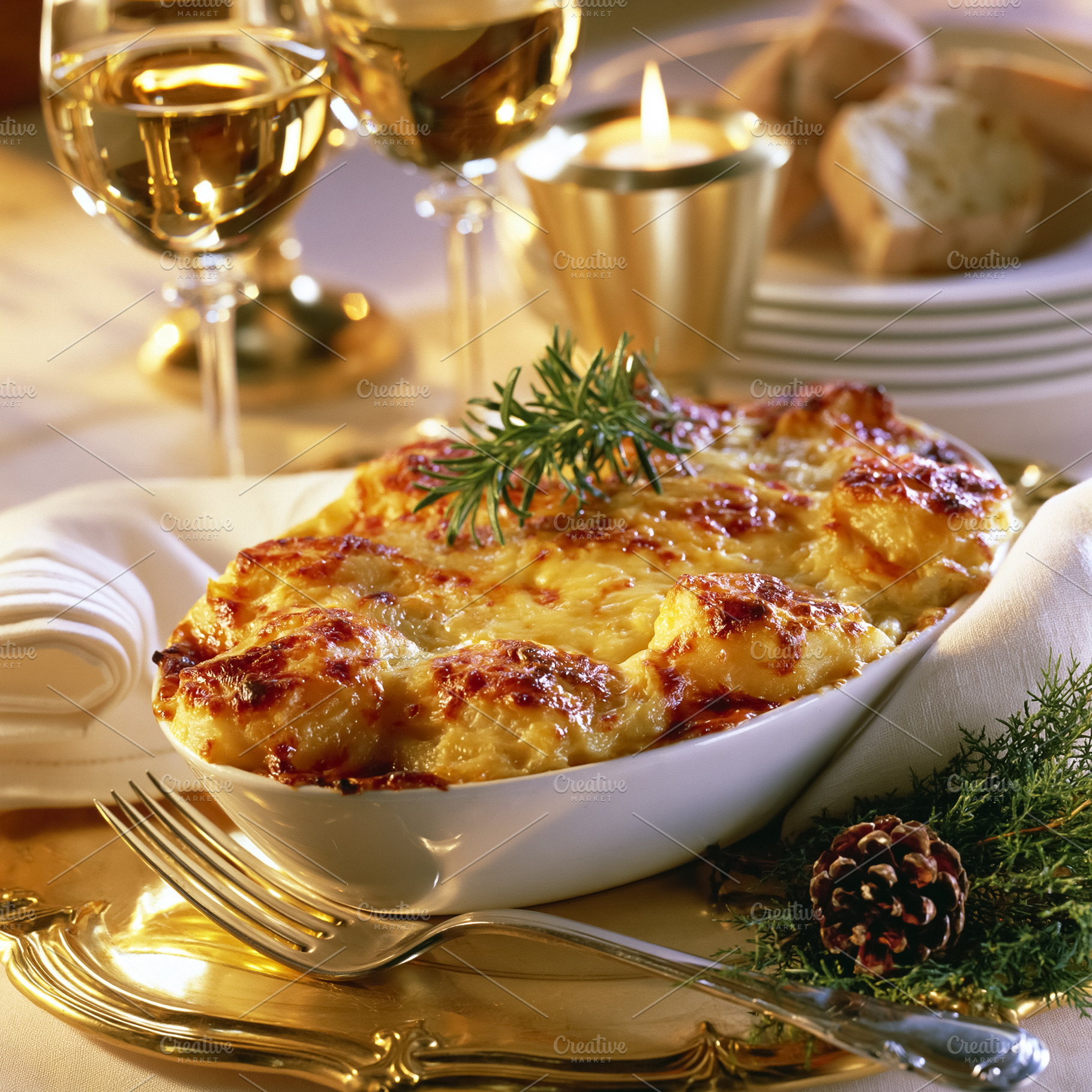 Potato gratin with rosemary sprig ready for a holiday dinner, featuring wine gl, a Photo by Studio ANNA