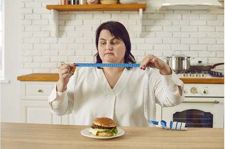 Fat overweight young woman sitting, a Food & Drink Photo by StudioRomantic