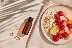 Healthy breakfast composition with fruits, oats, and essential oil on a neutral, a Photo by AlyaAnd