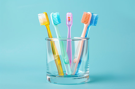 New toothbrushes in glass on blue background, a Health & Medical Photo by AlyaAnd