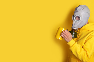 Individual wearing a gas mask and yellow hoodie drinks from a ma, a Person Photo by Ales Munt
