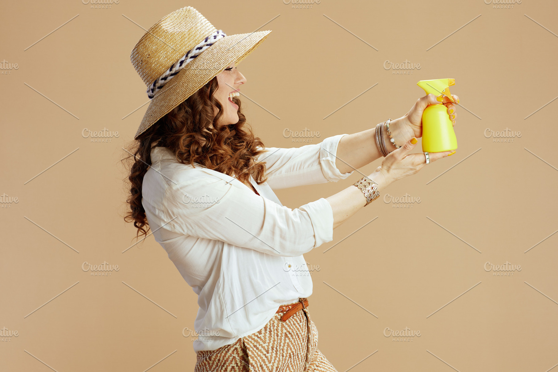 smiling female in blouse and shorts aiming as gun on beige, a Person Photo by Alliance Images