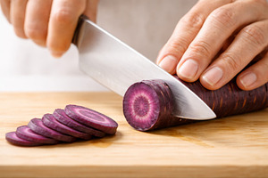 Slicing purple carrot on wooden boar, a Photo by Dvoevnore photos
