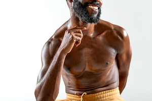 Happy black shirtless gay model sitting on stool in white studio, a Person Photo by andreonegin market