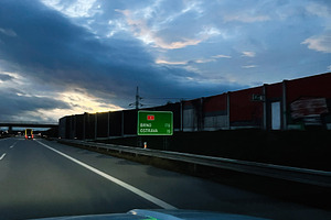 Driving at dusk on a highway toward Brno and Ostrava with a green road sign, a Photo by AS photostudio