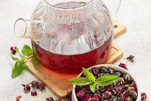 Glass teapot brewing herbal rosebud tea with mint, a Food & Drink Photo by Olena Rudo