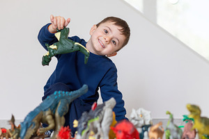 Happy child playing with dinosaur toys at home, a Person Photo by Antonio Gravante Market