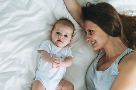 Young mother with baby girl on bed, a Person Photo by Galina_Zhigalova