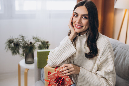 Beautiful happy woman unwrapping New Year or Christmas presents