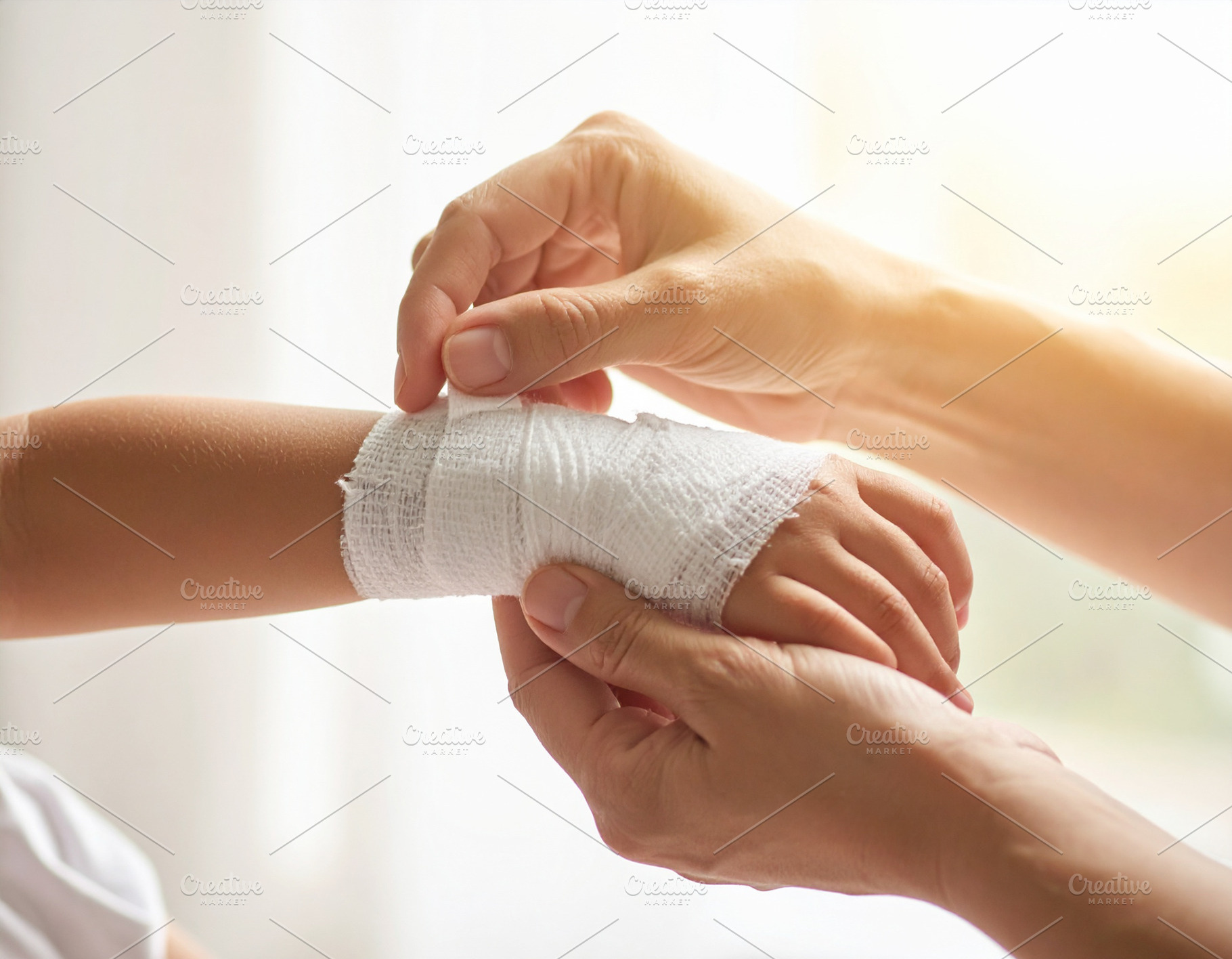 Adult hand placing a bandage on a child  wrist, a Person Photo by DanFLCreativo