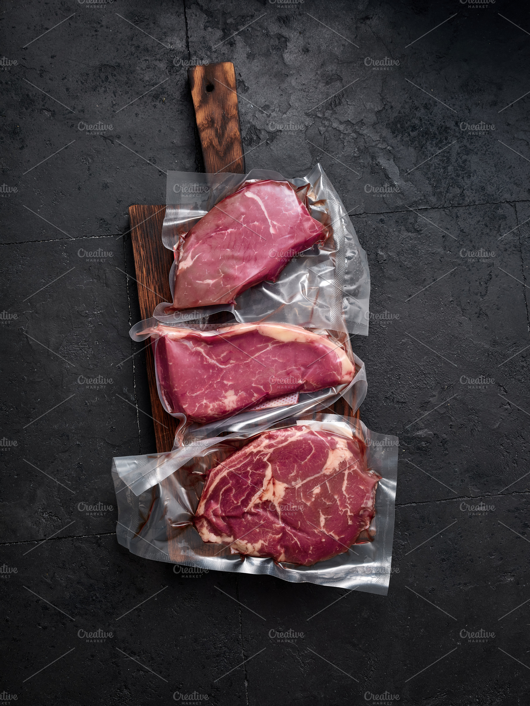 Raw rib-eye, roast beef, flank and rump steak are arranged on wooden board in a, a Food & Drink Photo by Asya Nurullina