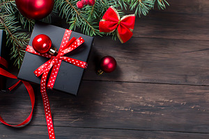 Black christmas gift box with red ribbon and fir branches