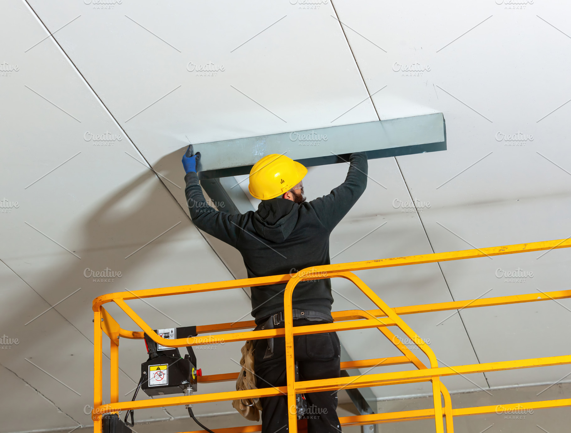 Worker installing metal profile for large plasterboard ceiling, an Industrial Photo by Antonio Gravante Market