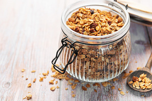 Granola breakfast cereal in glass jar with spoon, a Food & Drink Photo by Olena Rudo