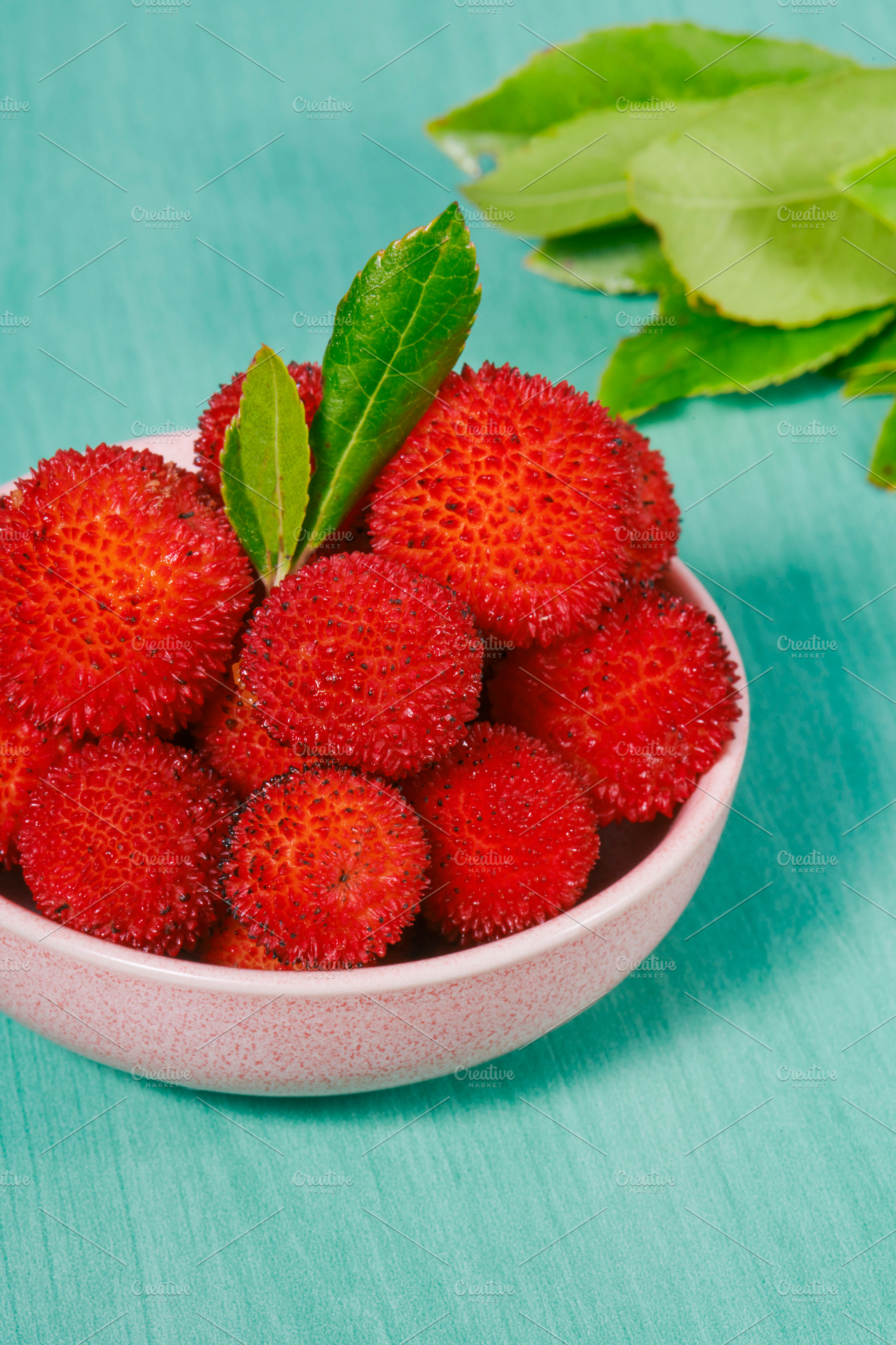 arbutus berries in a pink ceramic bowl with leaves, a Photo by Nito