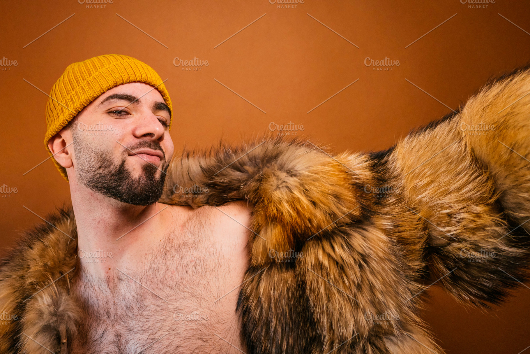 Assertive man posing with fur coat and beanie, a Photo by karrastock