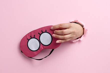 pink textile sleep mask in a female hand sticking out of a bull, an Abstract Photo by ndanko
