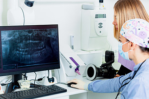 Dentists examining a dental radiography on a computer in a denta, a Health & Medical Photo by Antonio Gravante Market