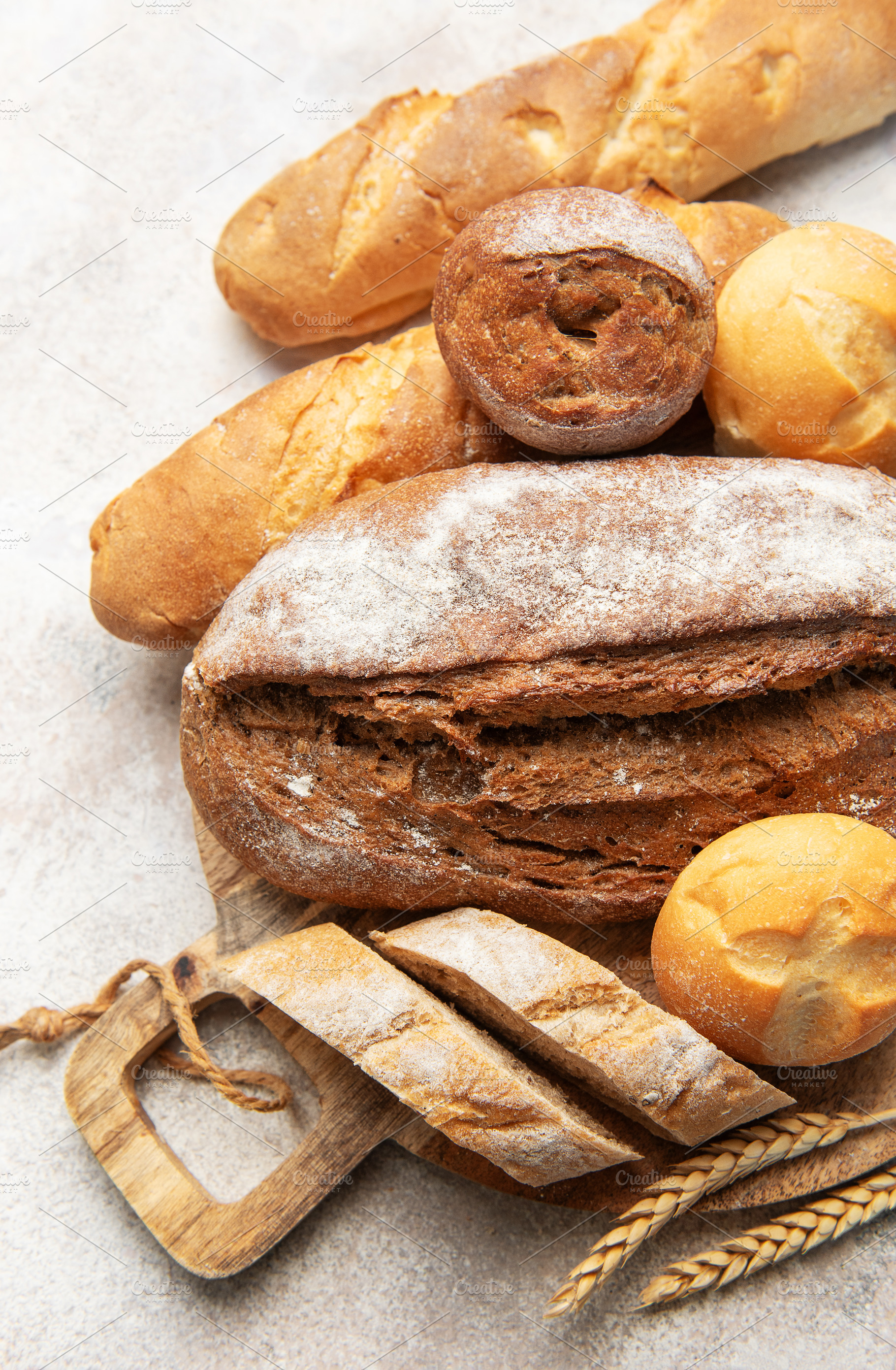 Assortment of fresh baked bread on rustic wooden board, a Food & Drink Photo by Olena Rudo