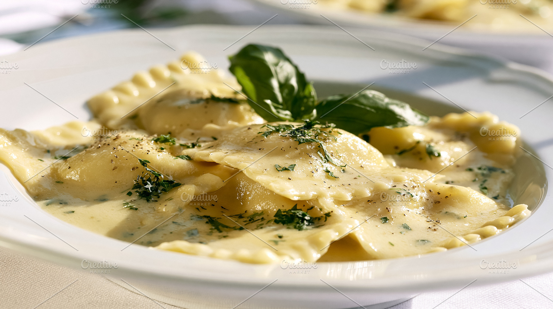 Ravioli pasta served in a creamy sauce with fresh basil and herbs, italian trad, a Photo by Studio ANNA