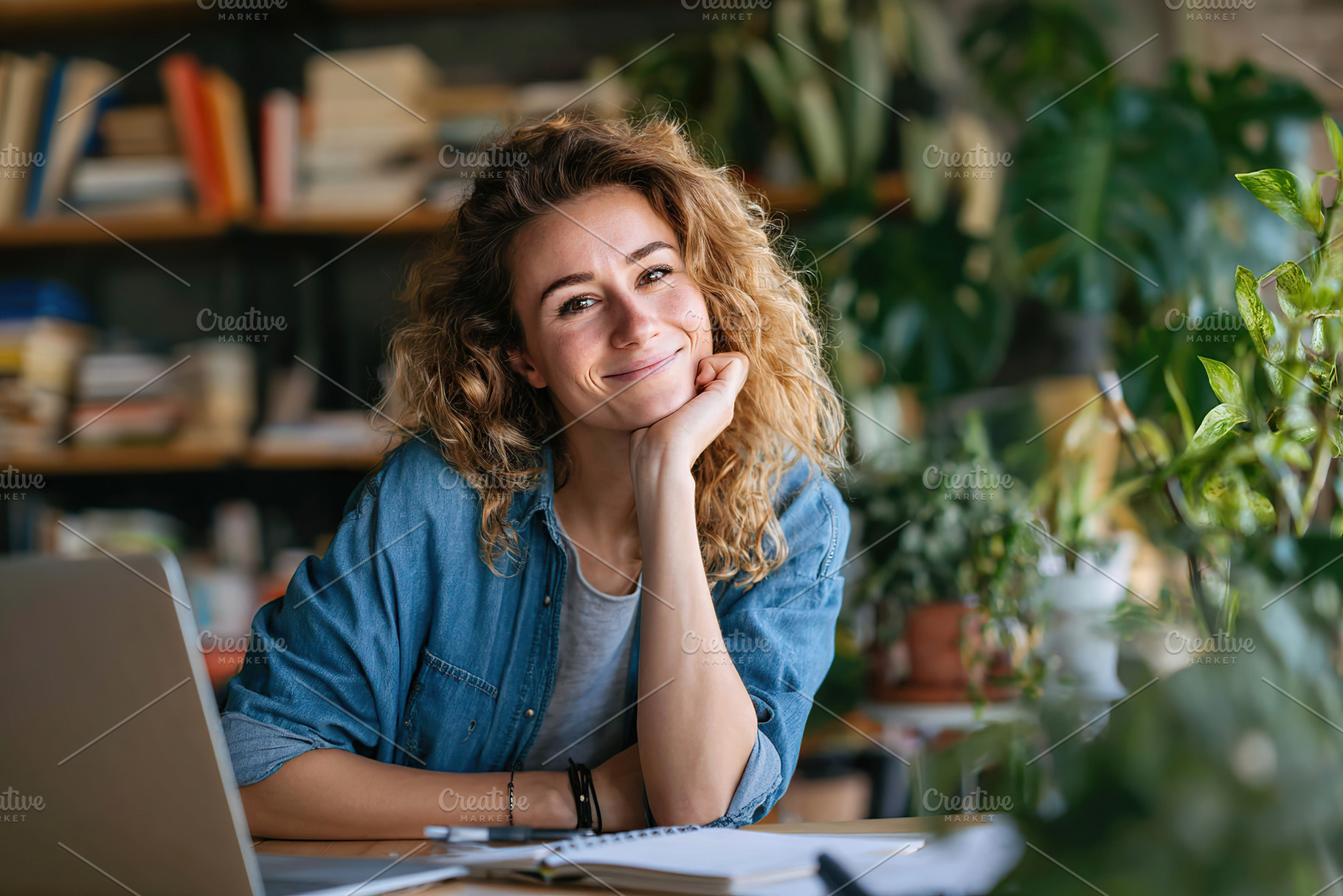 Woman engaged in a video call from her home workspace surrounded by plants and, a Person Photo by AlyaAnd