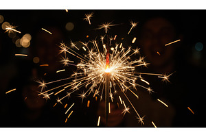 Hand holds a single, lit sparkler, a Holiday Photo by Igor Tichonow