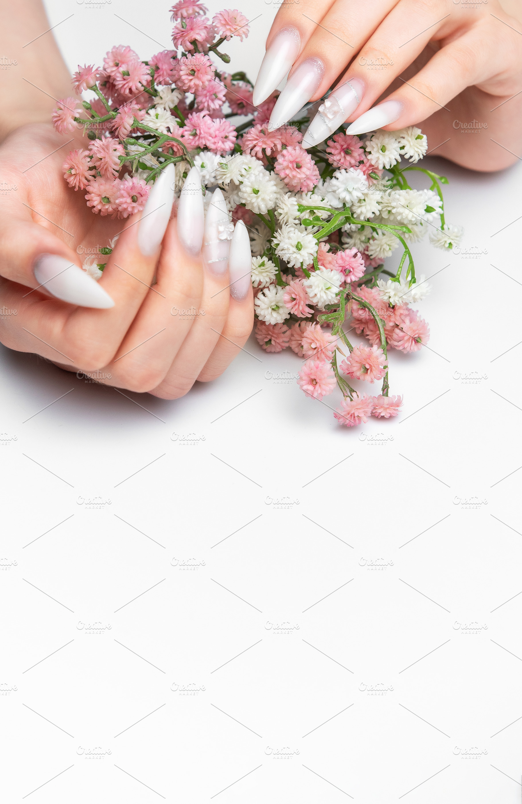 Woman's hands holding flowers with stiletto nail art manicure, a Photo by Olena Rudo