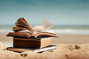 Open book placed on sandy beach with ocean background. Concept o, a Photo by salmon.black