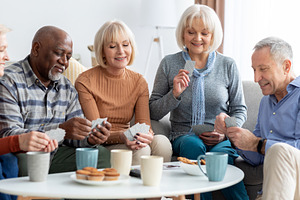 Happy senior people playing cards at nursing home, a Photo by Prostock-Studio