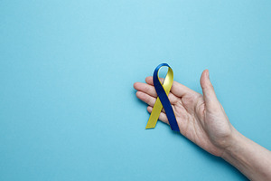A person holds a yellow and blue awareness ribbon, symbolizing World Down Syndr, a Photo by matucha