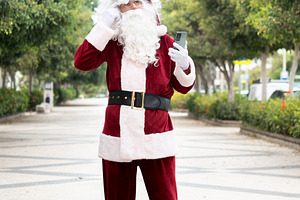 Lost Santa Claus checking smartphone for directions beside gift sack, a Person Photo by etorres69