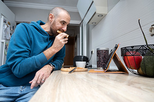 Man having toast for breakfast while using a tablet at home, a Food & Drink Photo by etorres69
