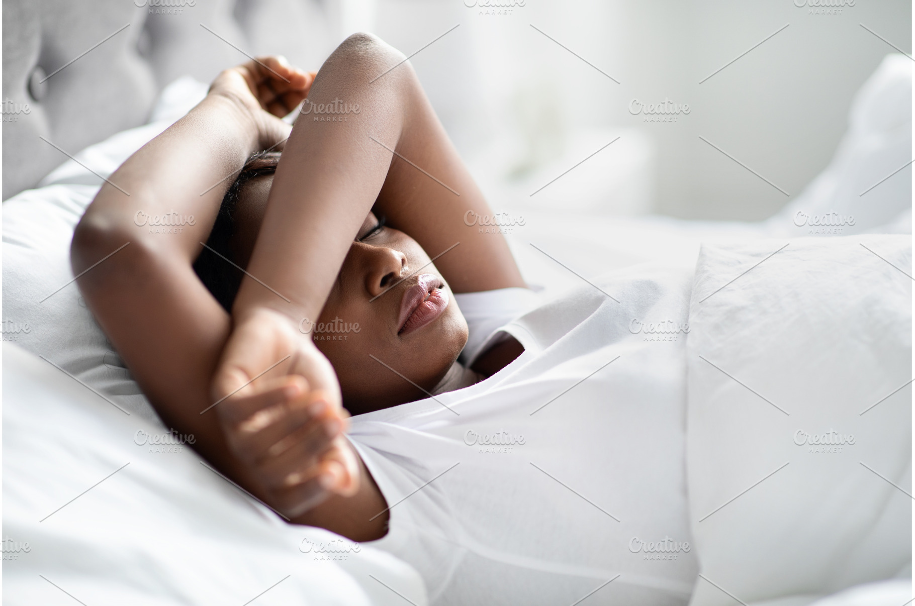 Sad black woman laying in bed with, a Person Photo by Prostock-Studio