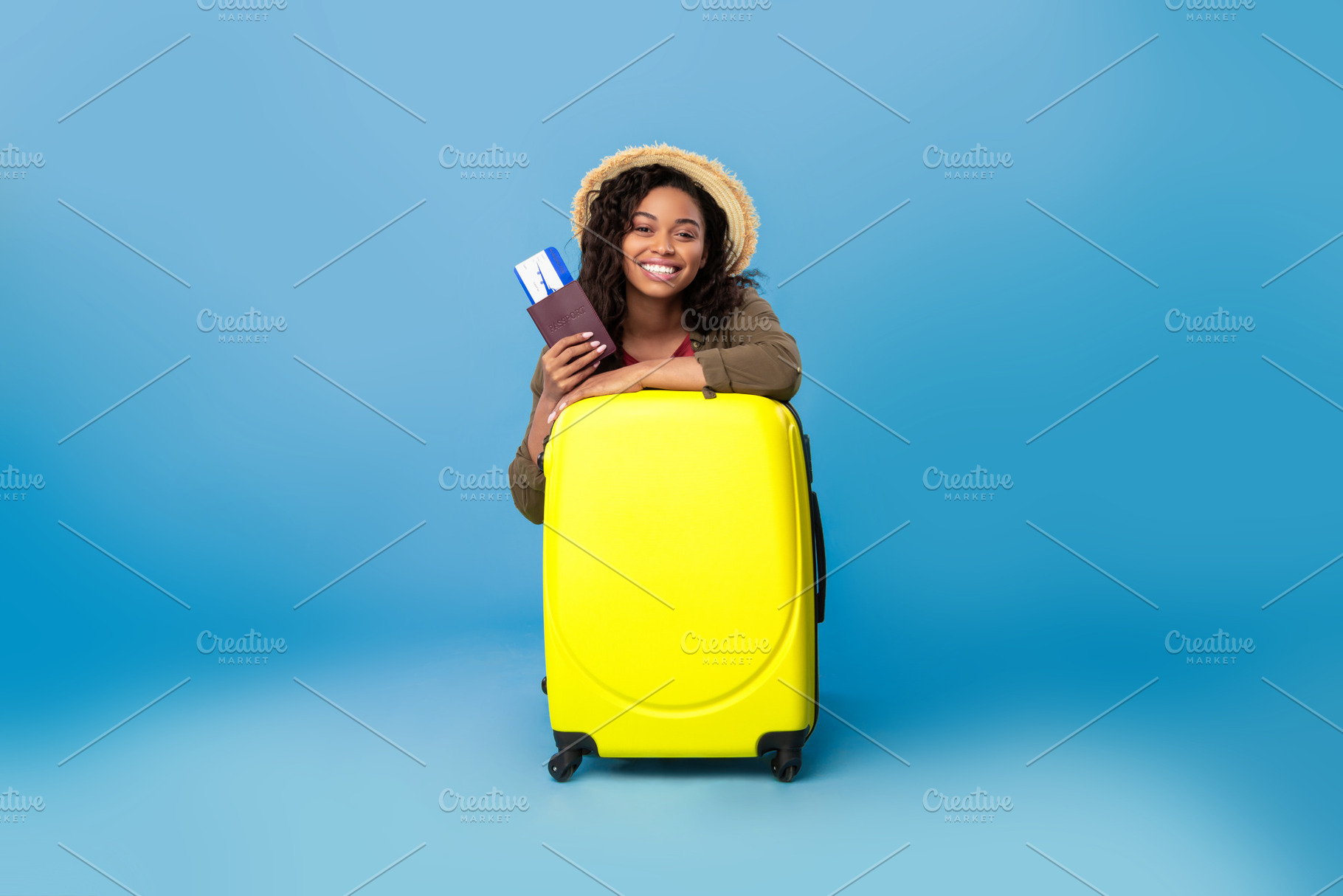 Happy black lady in casual wear sitting behind suitcase, holding passport and f, a Photo by Prostock-Studio