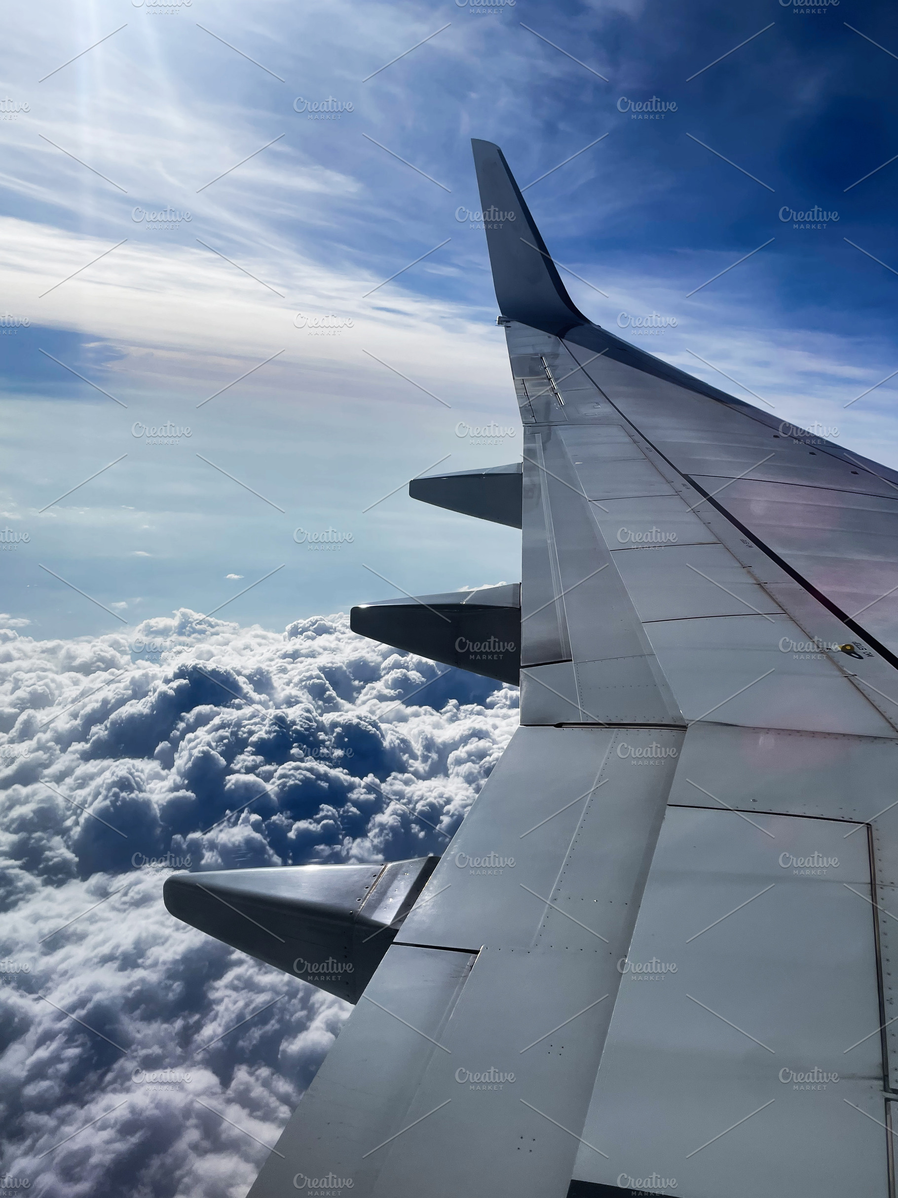 Airplane wing view over fluffy clouds with blue sky and sunlight, a Photo by AS photostudio