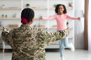 Unrecognizable black girl running towards woman in military uniform, a Photo by Prostock-Studio