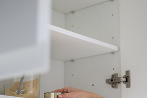 Woman taking food container from kitchen cabinet in minimalist home interior, a Food & Drink Photo by etorres69