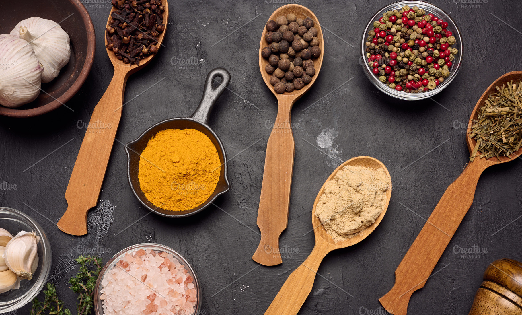 Various ground spices in wooden spoons, olive oil on dark table, a Food & Drink Photo by ndanko