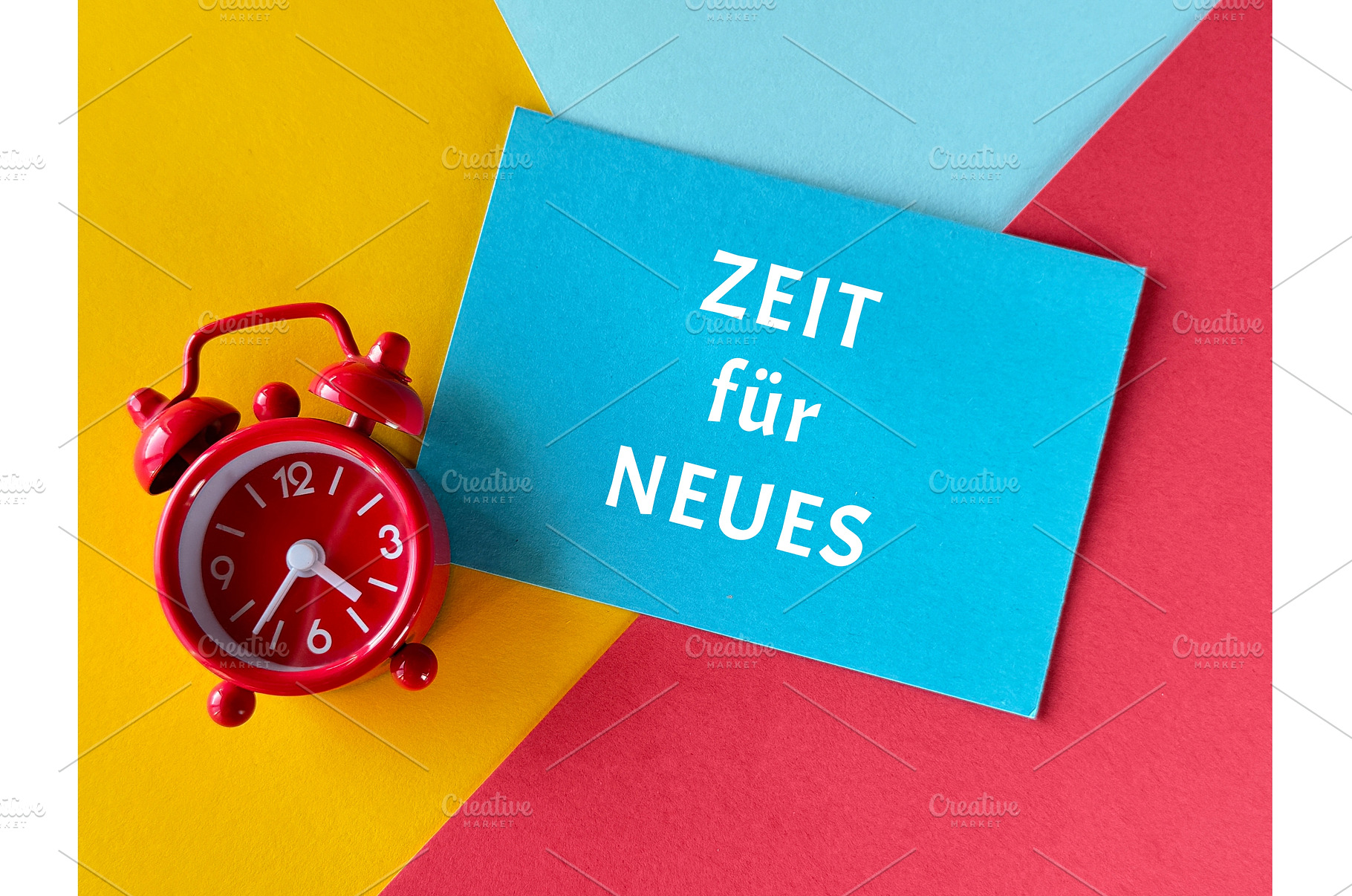 Red alarm clock and blue card with, a Photo by tilialucida