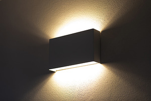 Modern wall lamp illuminating a textured wall in a dark room, an Architecture Photo by Antonio Gravante Market