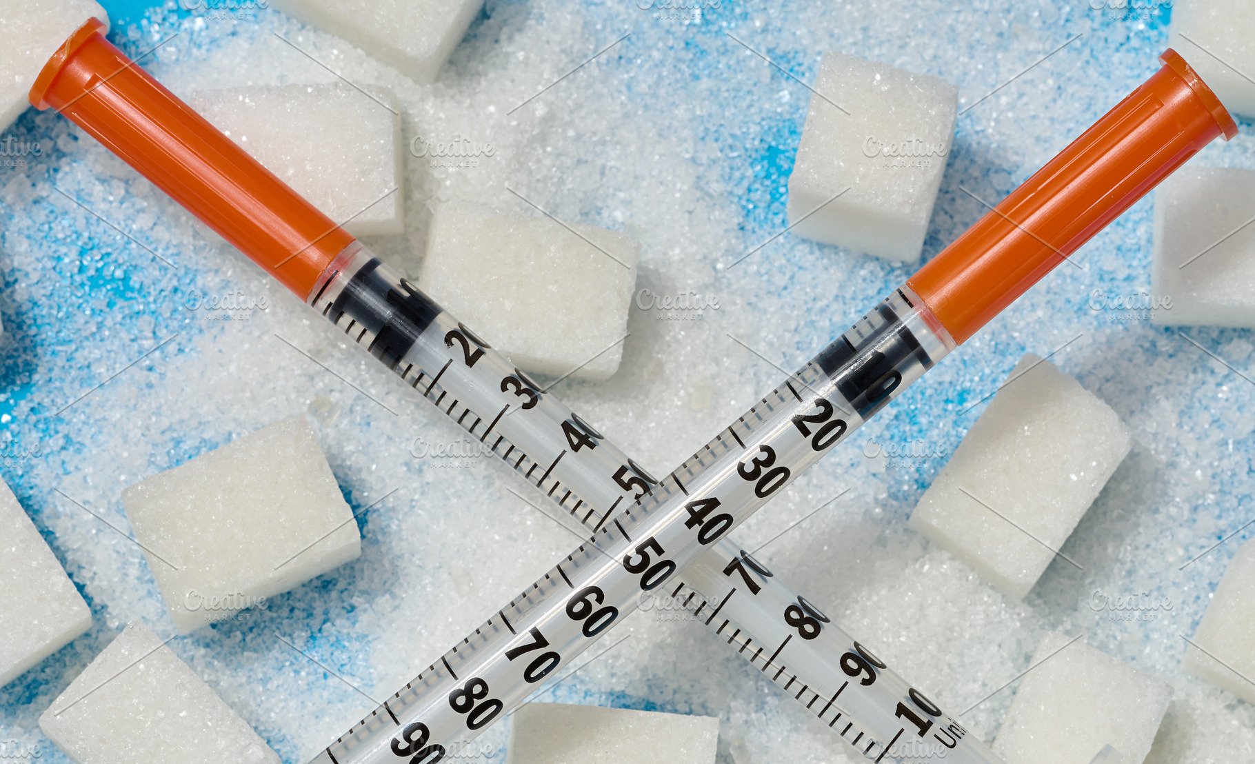 Two insulin syringes crossed over cubes and scattered white suga, a Health & Medical Photo by ndanko