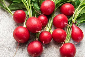 Fresh harvested red radishes with green leaves on concrete, a Food & Drink Photo by Olena Rudo