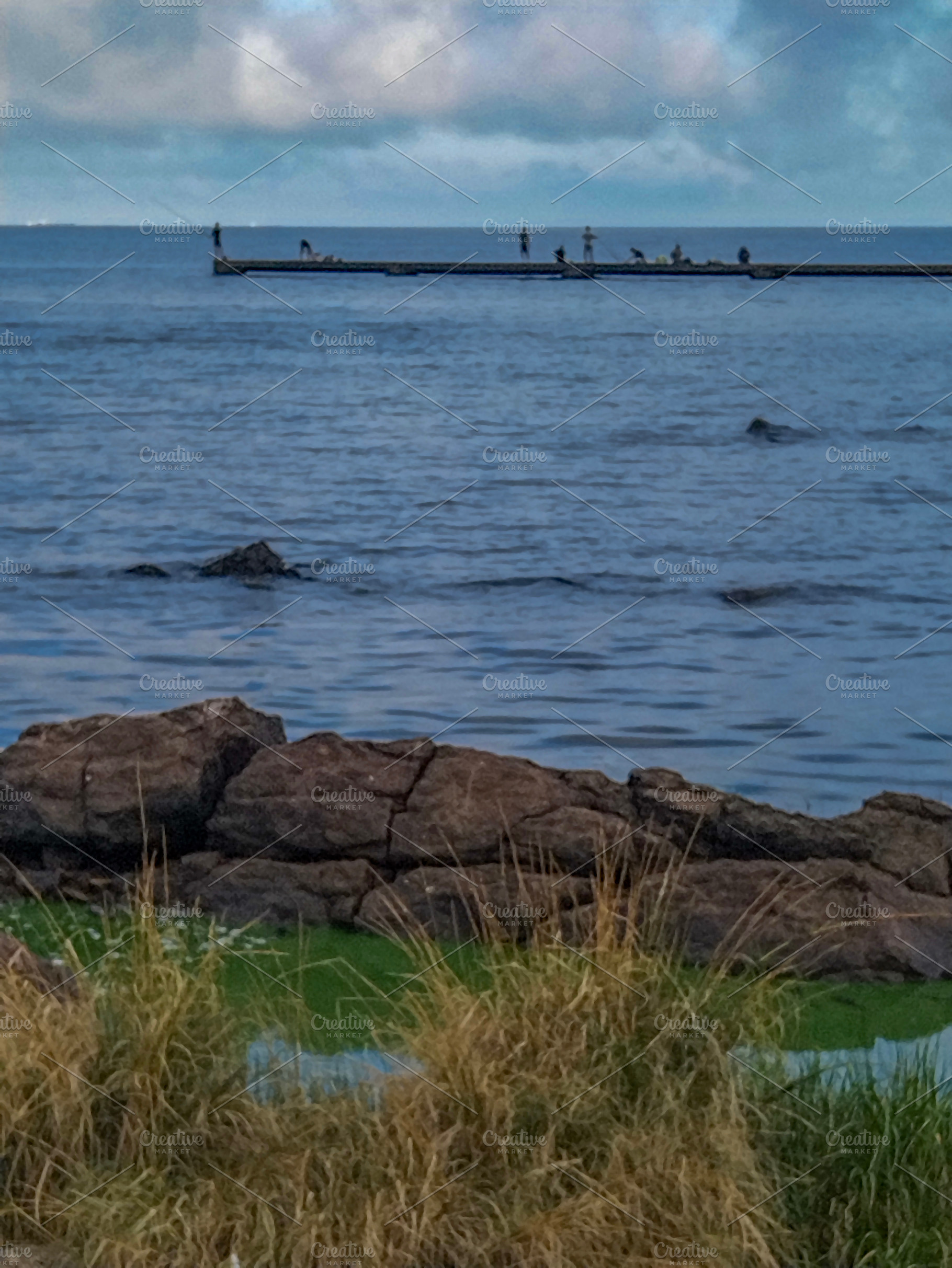 Calm seascape with distant pier and rocks, a Nature Photo by DanFLCreativo