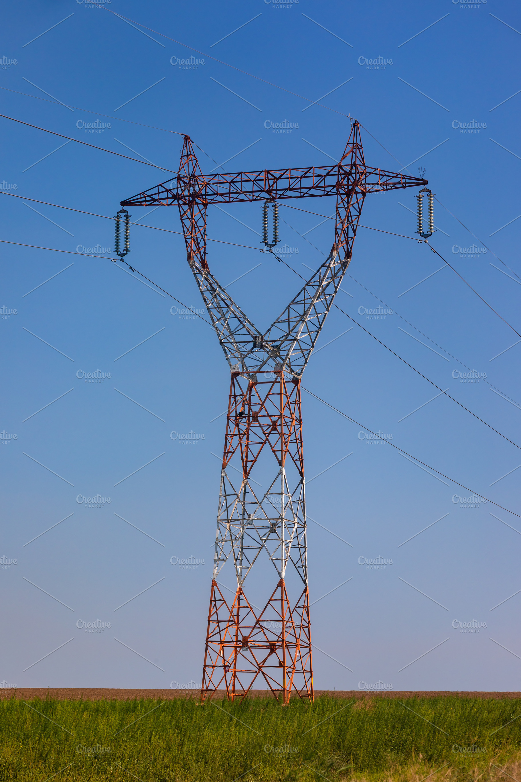 Steel electricity pylon standing in a green field under a clear blue sky, symbo, a Technology Photo by Ales Munt