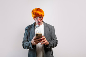 Adult man looking at smartphone with shocked expression, a Person Photo by karrastock