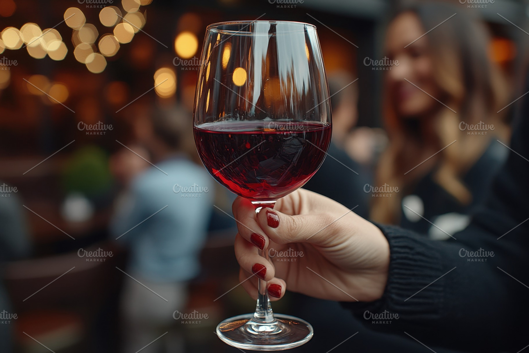 Hand holding a glass of red wine in, a Photo by Tanuart