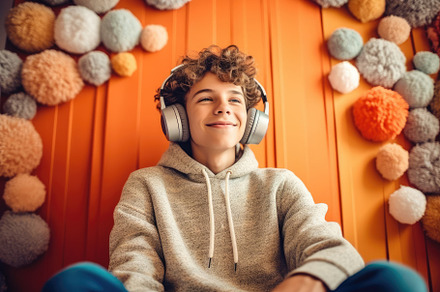 Adolescent boy listening to music with fun headphones in his roo, a Person Photo by designvectx