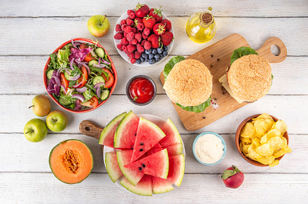 Tasty summer barbecue table with hamburgers, salads, fruits and