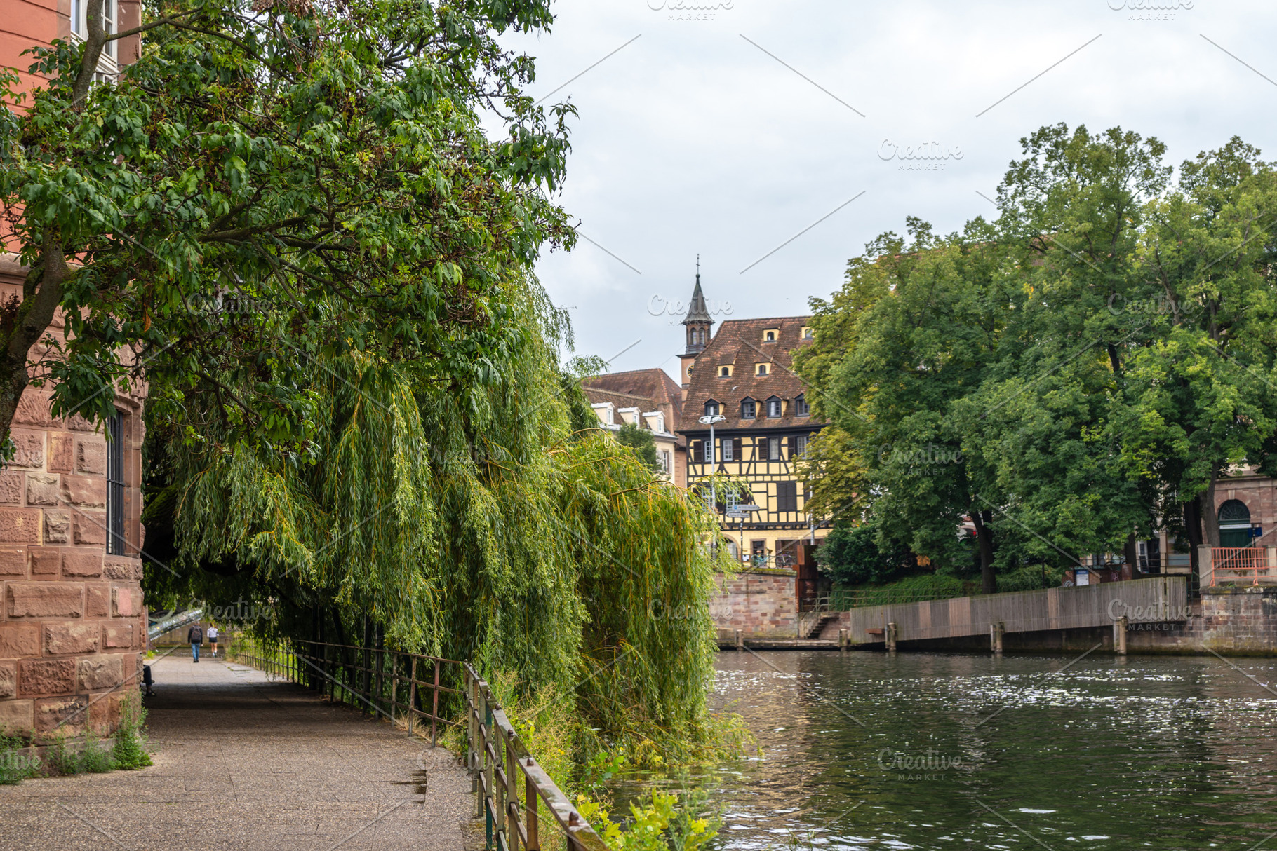 Tree-lined riverside path and historic buildings Strasbourg, Fra, an Architecture Photo by GoodGoods